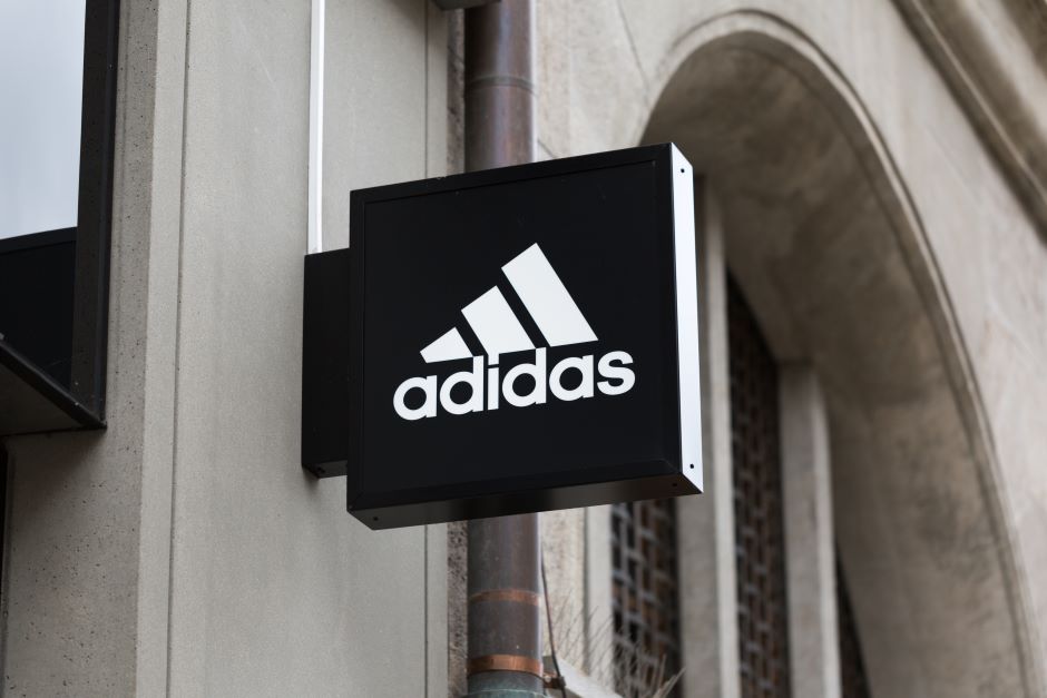 Placa externa em parede de prédio com a logomarca da marca Adidas